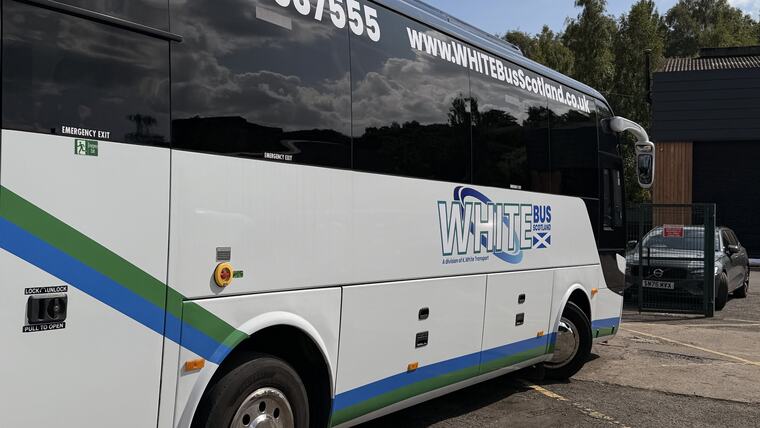 The side of the White Bus Scotland coach in the fleet livery, parked at the yard